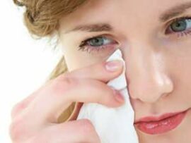 Woman wiping eye with a tissue