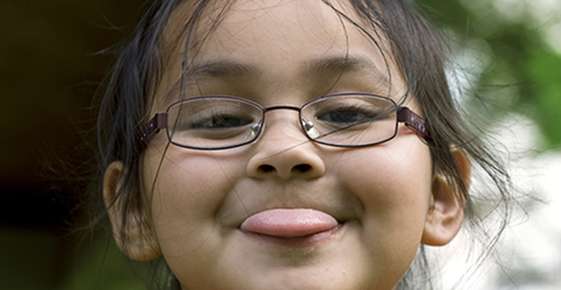 Little girl wearing glasses sticking her tongue out
