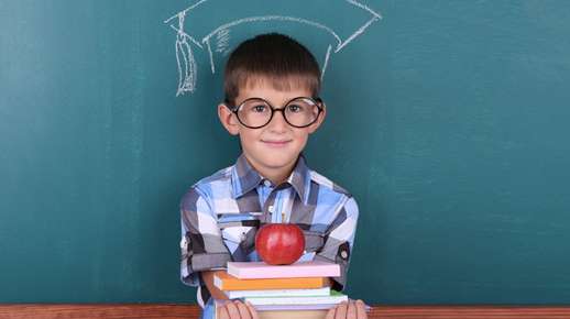 Boy wearing glasses in front of a chalkboard