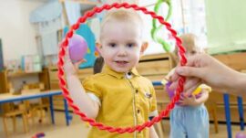 Kid throwing a ball through a ring