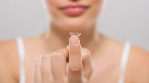 Women holding contact lens on a finger tip
