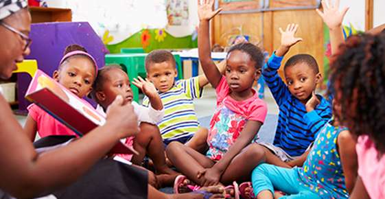 Kids sitting in a circle with hands raised