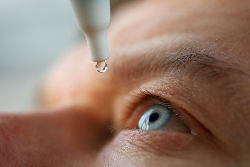 Person putting drops in their eyes