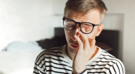 Man rubbing his eyes under glasses