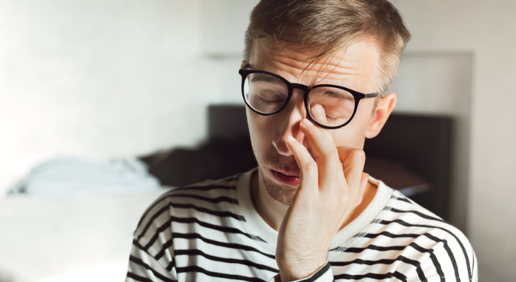 Man rubbing his eyes under glasses