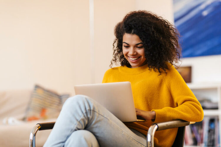 woman using laptop while sitting on chair in living room