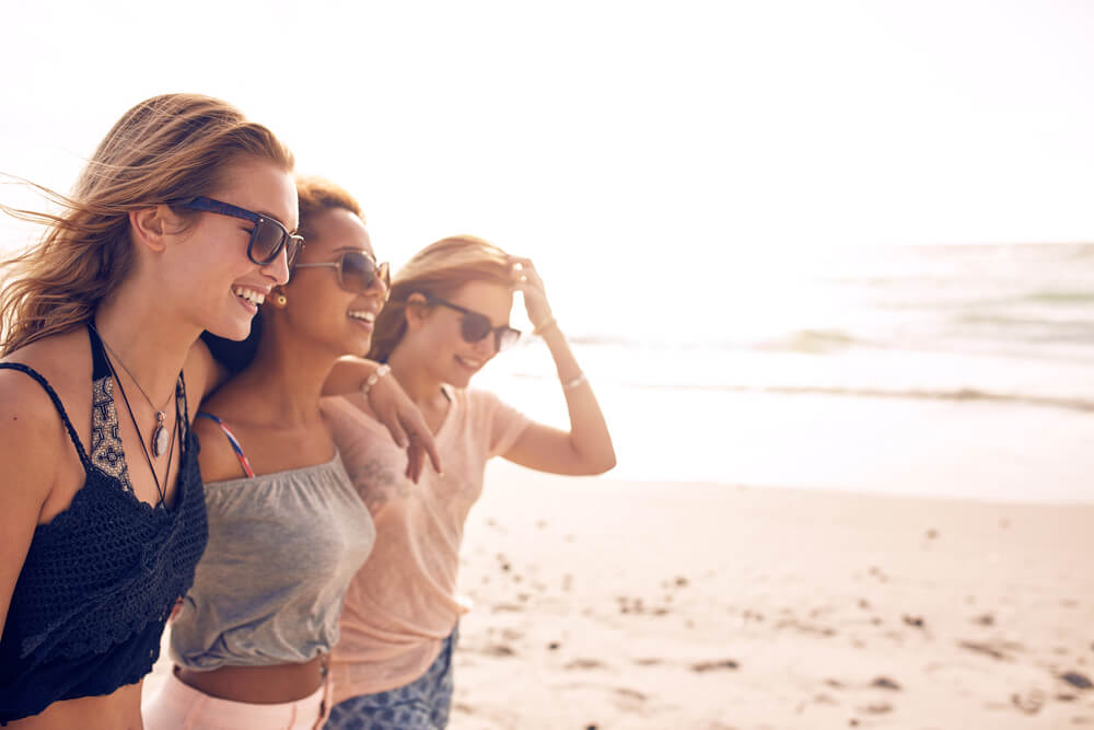 3 woman in sunglasses walking on the beach
